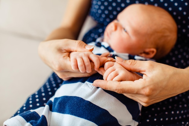 Admirable vue rapprochée des mains du nouveau-né tenues par les mains fortes et sûres de la mère, concept de sécurité familiale