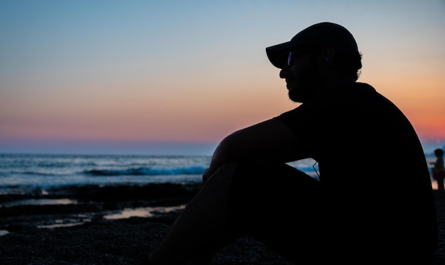 Ado silhouette assis à la plage en paix