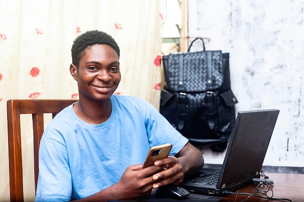 Adolescent africain tenant un téléphone portable à portée de main tout en regardant la caméra