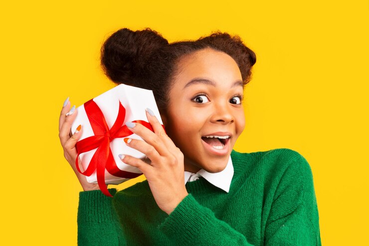 Photo un adolescent afro excité secouant une boîte à cadeaux au studio.
