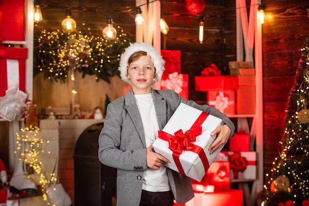 Un adolescent aide le père Noël avec des cadeaux. visitez Santaland ce jour férié. pays des merveilles d'hiver au pôle nord. petit garçon fête le nouvel an dans la résidence du père Noël. rêve d'enfance. meilleur cadeau de Noël.