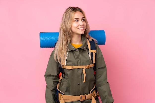 Adolescent alpiniste fille avec un gros sac à dos sur rose rire