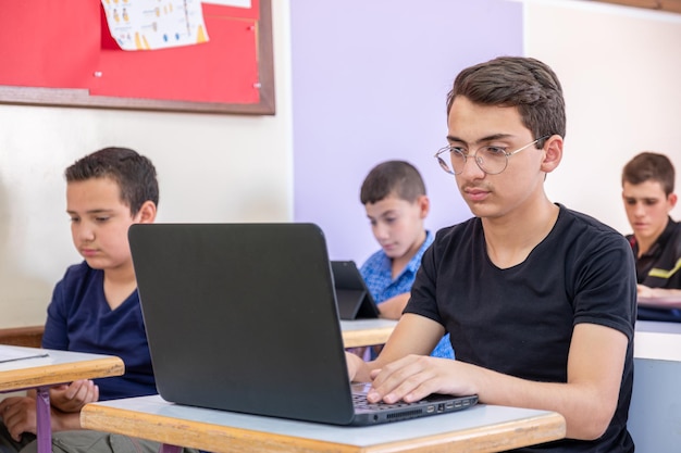 un adolescent arabe utilisant un ordinateur portable alors qu'il étudie à l'école