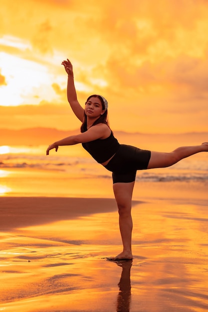 Un adolescent asiatique dansant le ballet en noir pour un festival au bord de la plage