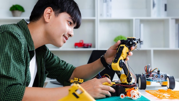 Adolescent asiatique faisant le projet de devoirs de bras de robot dans la maison