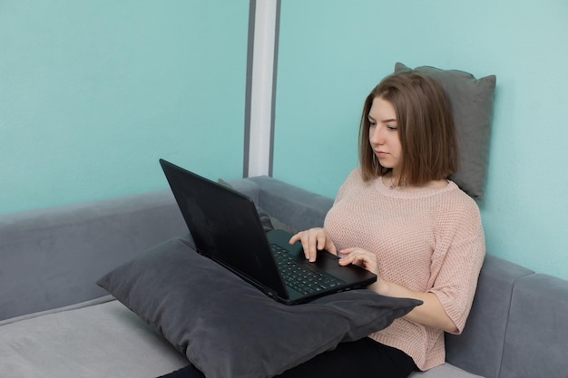 Un adolescent assis sur un lit devant un ordinateur portable avec l'intention d'apprendre à vivre en ligne