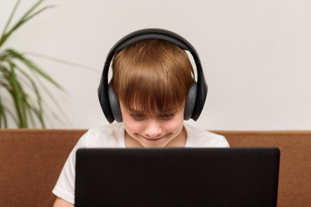 Adolescent assis avec un ordinateur portable dans les écouteurs. Dépendance aux jeux informatiques