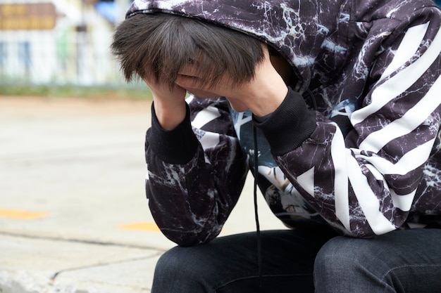 Adolescent assis se baisser la tête. Il se sent frustré et dépressif majeur.