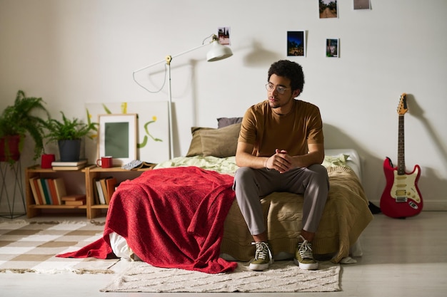 Adolescent assis seul dans sa chambre