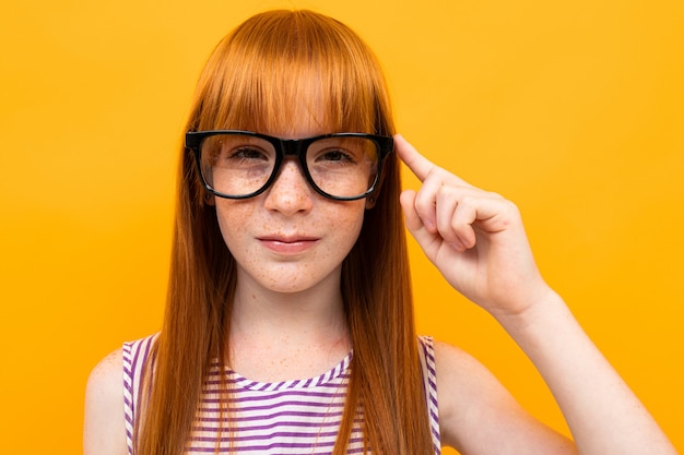Adolescent aux cheveux roux dans le mur orange avec des lunettes pour la vision