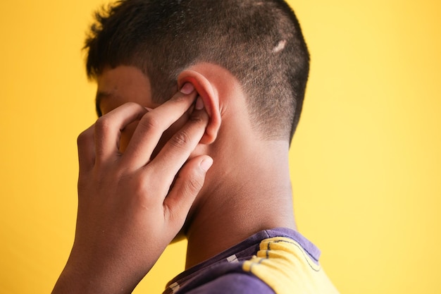 adolescent ayant des douleurs à l'oreille touchant son oreille douloureuse