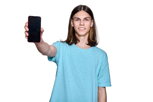 Adolescent beau mec montrant un écran de smartphone vierge sur fond blanc isolé Étudiant adolescent souriant posant dans un espace d'écran vide de studio pour la publicité de logo de texte