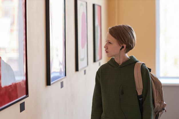 Adolescent blond regardant des images dans la galerie d'art