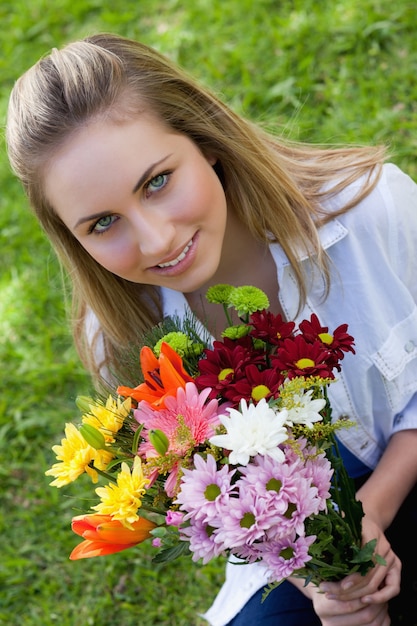 Adolescent blonde séduisante tenant un beau bouquet de fleurs