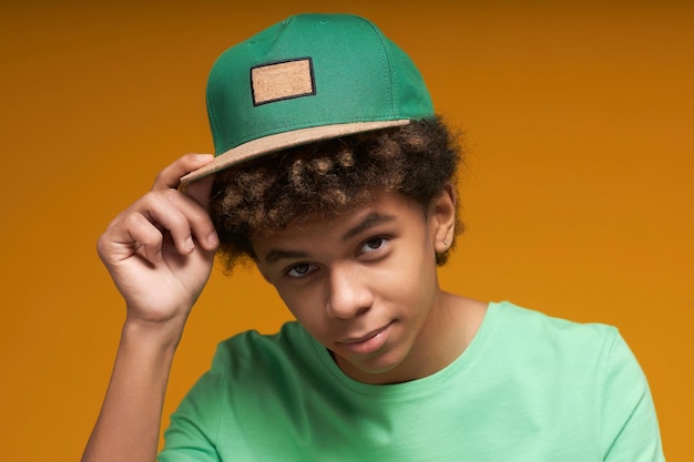 Photo adolescent calme touchant la visière de la casquette de baseball verte