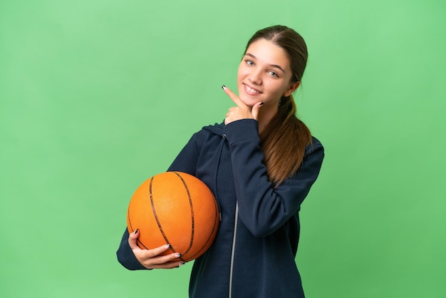 Adolescent caucasien fille jouant au basket-ball sur fond isolé heureux et souriant