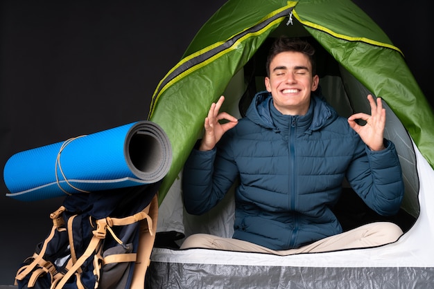 Adolescent, caucasien, homme, intérieur, camping, vert, tente, isolé, noir, mur, zen, pose