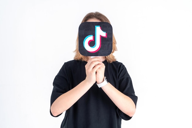 Photo adolescent caucasien tenant une image de logo tiktok dans ses mains sur un fond blanc