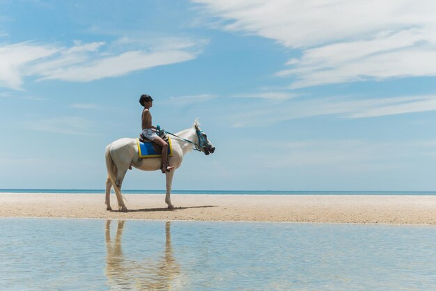 Photo un adolescent chevauche un cheval sur la plage