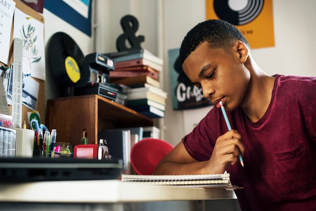 Adolescent dans une chambre à coucher faisant le travail en pensant