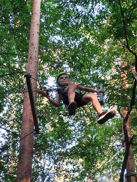 Un adolescent dans un parc de corde dans un parc d'attractions se déplace sur un pont suspendu Vue de dessous