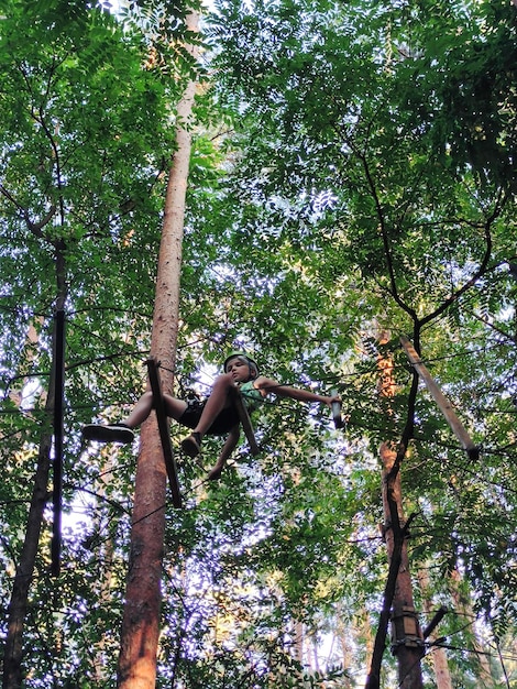 Photo un adolescent dans un parc de corde dans un parc d'attractions se déplace sur une rampe suspendue vue de dessous