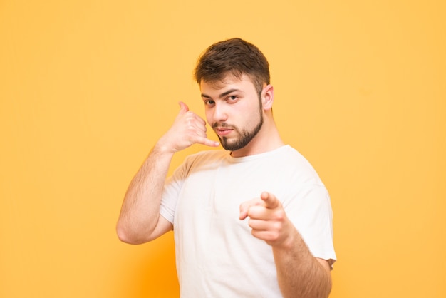 Adolescent dans un T-shirt blanc montre un doigt isolé sur jaune