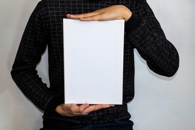 Un adolescent dans une veste à carreaux tient un rectangle blanc pour votre publicité