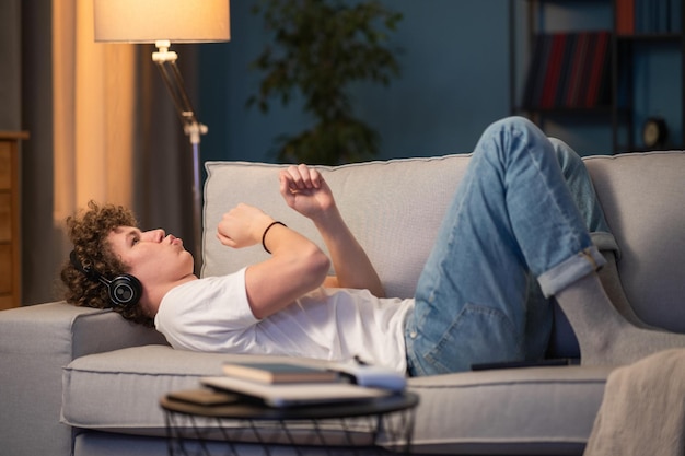 L'adolescent danse en agitant les bras allongé sur le canapé au rythme de la mélodie