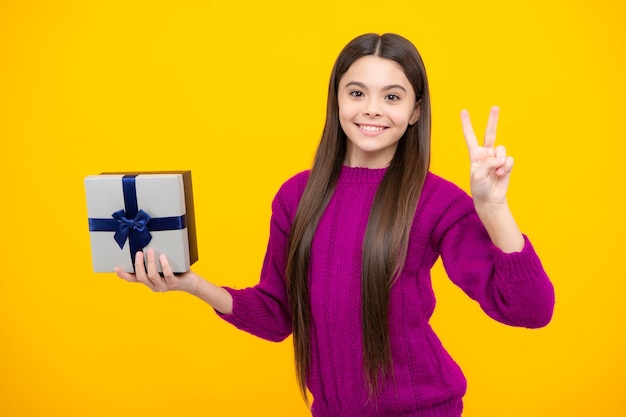 Adolescent enfant girl holding present box isolé sur fond jaune studio Concept de voeux et de cadeaux présent Concept de vacances d'anniversaire
