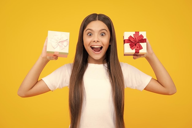 Adolescent enfant tenant une boîte-cadeau sur fond isolé jaune Cadeau pour les enfants anniversaire Noël ou nouvel an boîte cadeau Adolescent excité heureux émotions étonnées et ravies