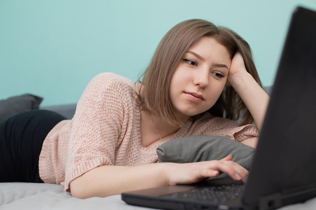 L'adolescent est allongé sur un lit pendant qu'il étudie pour l'examen dans la pièce.