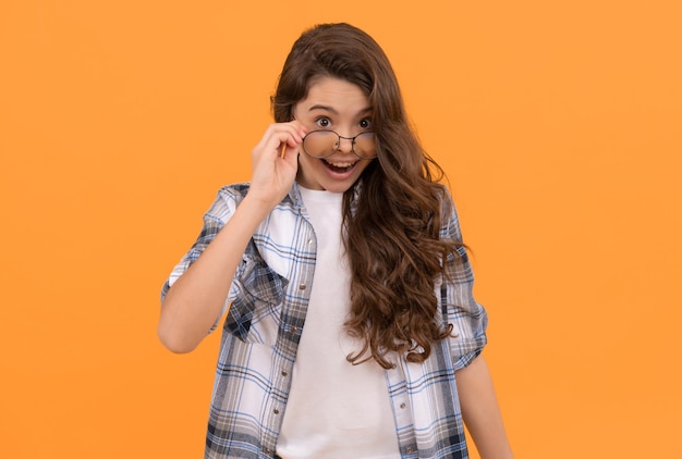 Adolescent étonné en chemise à carreaux et lunettes sur fond jaune