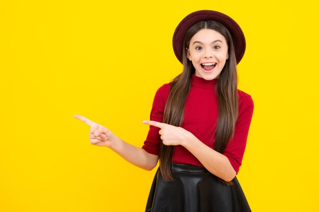 Adolescent excité heureux émotions étonnées et ravies Gros plan portrait d'adolescente enfant fille montrant à l'espace de copie pointant vers des publicités isolées sur fond jaune Espace de copie maquette