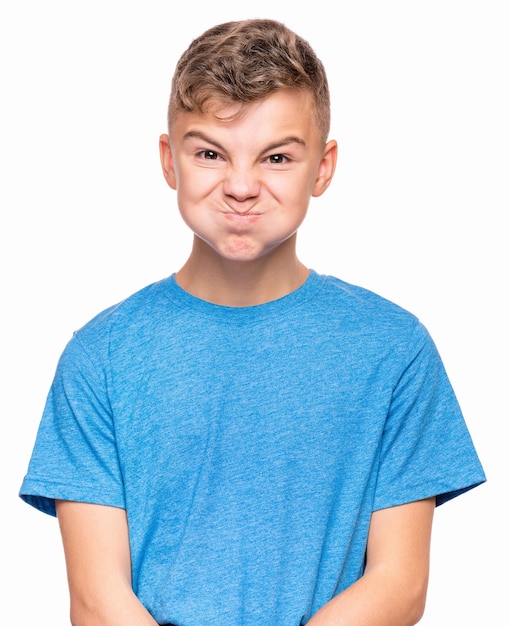 Adolescent faisant un visage drôle Portrait émotionnel à moitié d'un enfant portant un t-shirt bleu Enfant triste isolé sur fond blanc