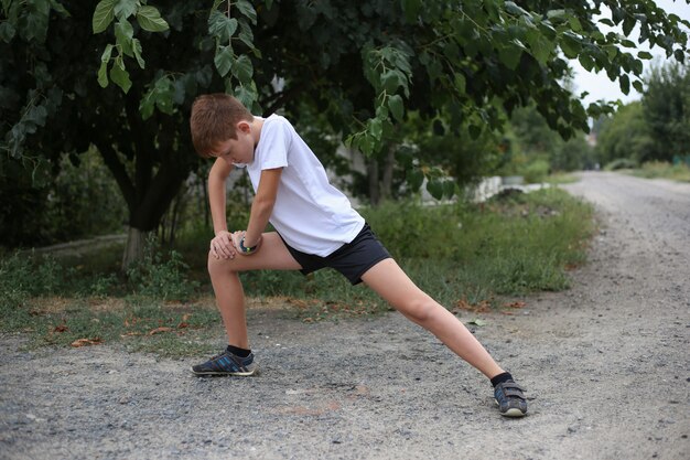 Un adolescent fait des exercices d'étirement pour les jambes à l'extérieur