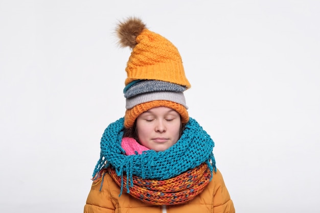 Photo adolescent femelle caucasien drôle dans plusieurs écharpes et chapeaux se détendre avec les yeux fermés.