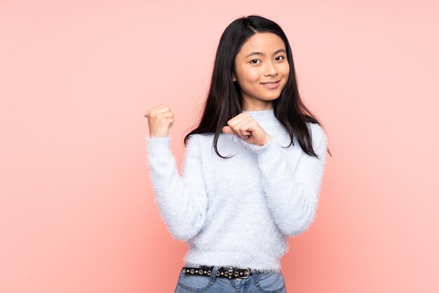 Adolescent femme chinoise sur mur rose pointant vers le côté