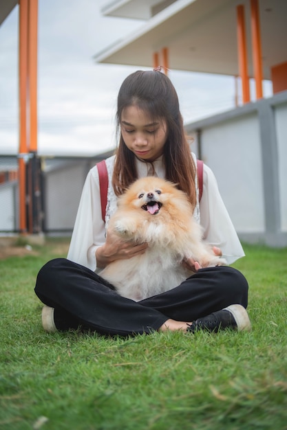 Adolescent, femme, jouer, pomperanian, chien, chez soi, femme asiatique, détendre, dehors