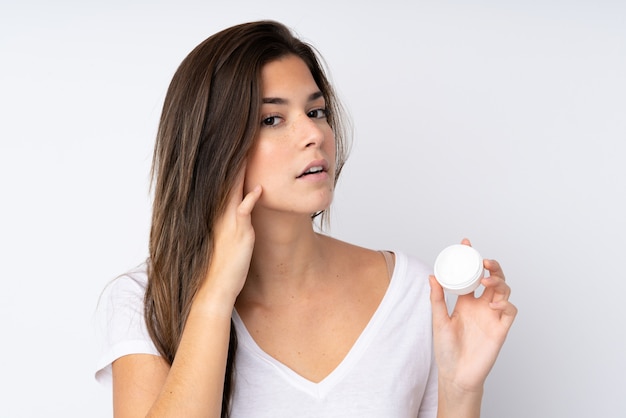 Adolescent femme sur mur isolé avec crème hydratante