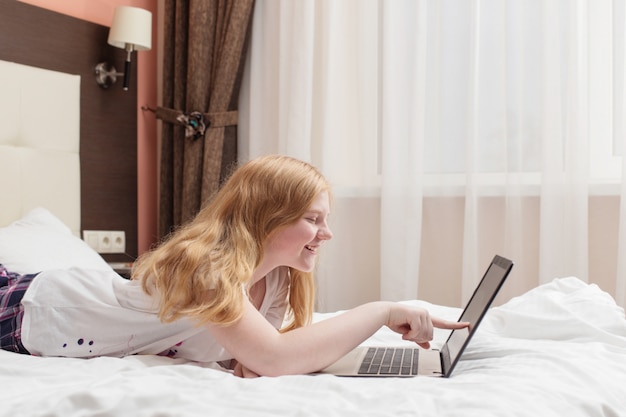 Adolescent fille avec ordinateur portable au lit