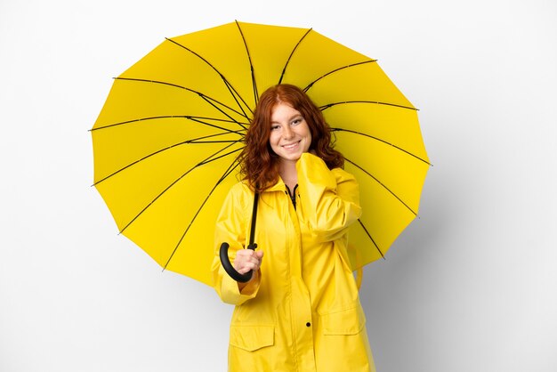 Adolescent fille rousse manteau imperméable et parapluie isolé sur fond blanc en riant