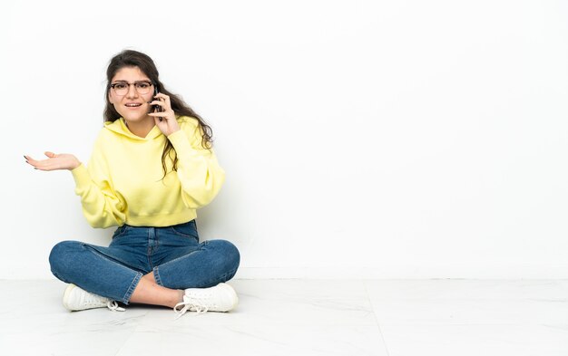 Adolescent fille russe assise sur le sol en gardant une conversation avec le téléphone mobile avec quelqu'un