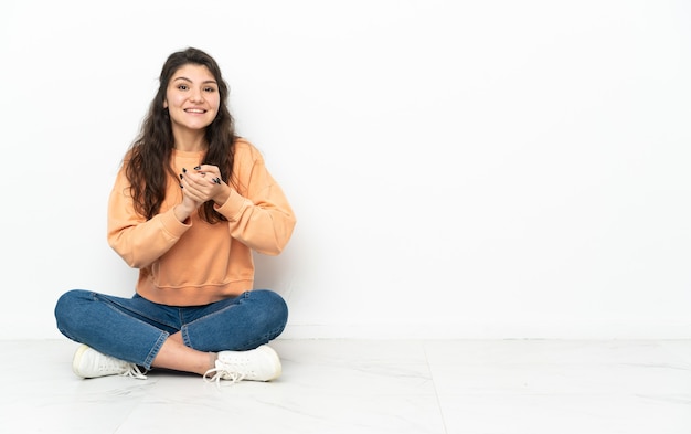 Adolescent fille russe assise sur le sol en riant