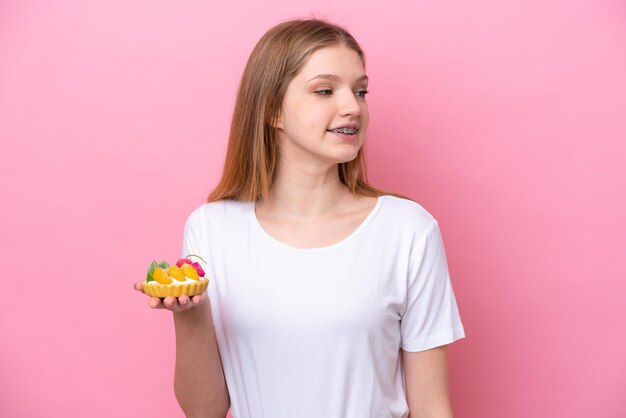 Adolescent fille russe tenant une tartelette isolé sur fond rose à côté