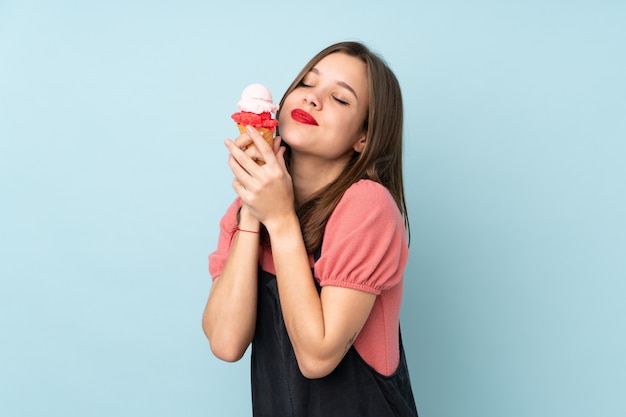 Adolescent fille tenant une glace au cornet isolé sur mur bleu