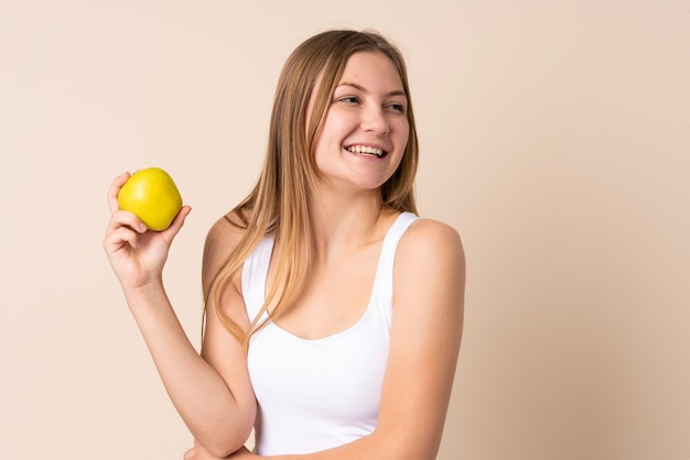 Adolescent fille ukrainienne isolée sur beige avec une pomme et heureuse