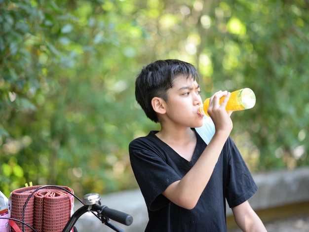 Adolescent garçon buvant du jus de fruit dans le parc camping l'heure d'été