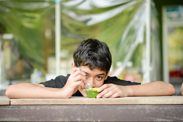 Adolescent garçon buvant du jus de fruit dans le parc camping l'heure d'été