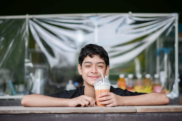 Photo adolescent garçon buvant du jus de fruit dans le parc camping l'heure d'été